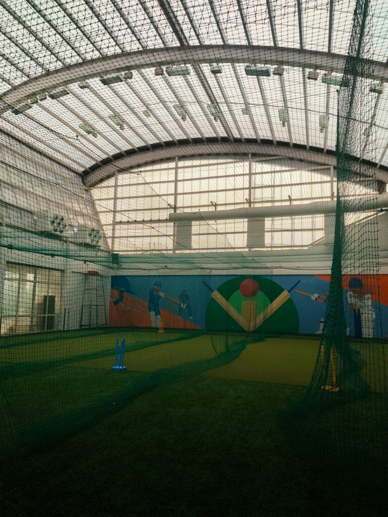 Cricket practice facility with vibrant murals in Dharamshala, India.